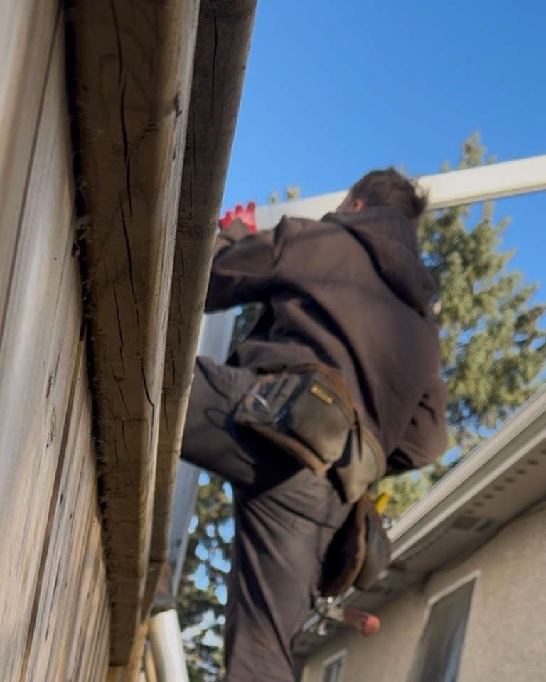Calgary gutter repair expert fixing residential eavestrough system safely on ladder